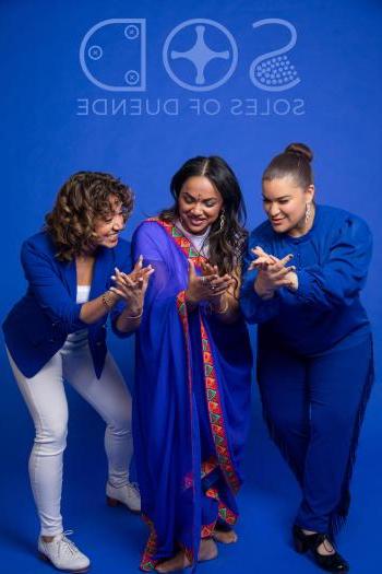 Three dancers in front of a blue background
